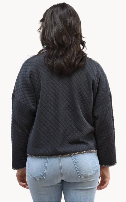 Back view of the quilted floral contrast zip-up jacket showing the mock neck, side pockets, and feminine detailing.