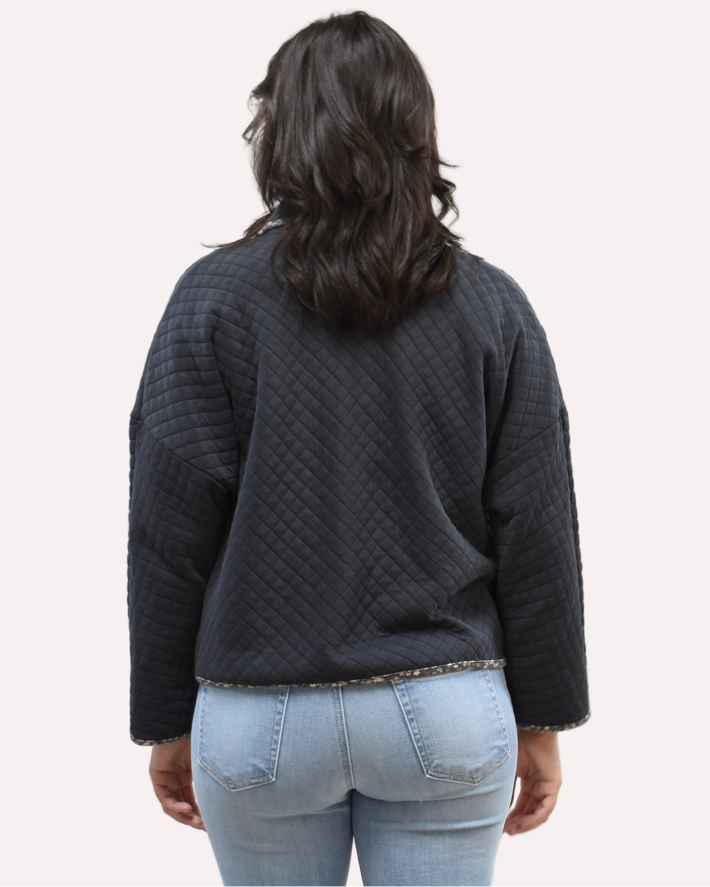 Back view of the quilted floral contrast zip-up jacket showing the mock neck, side pockets, and feminine detailing.