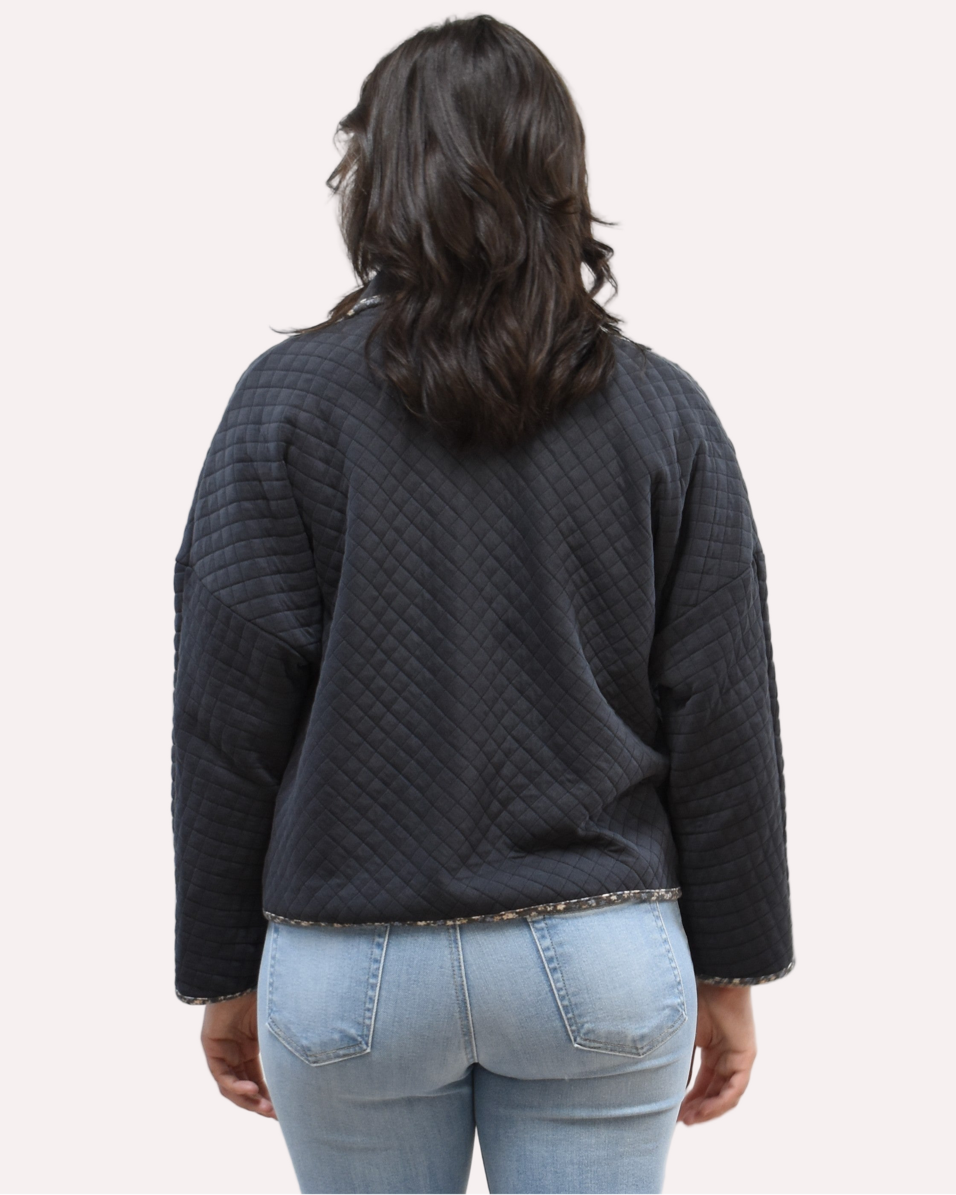 Back view of the quilted floral contrast zip-up jacket showing the mock neck, side pockets, and feminine detailing.