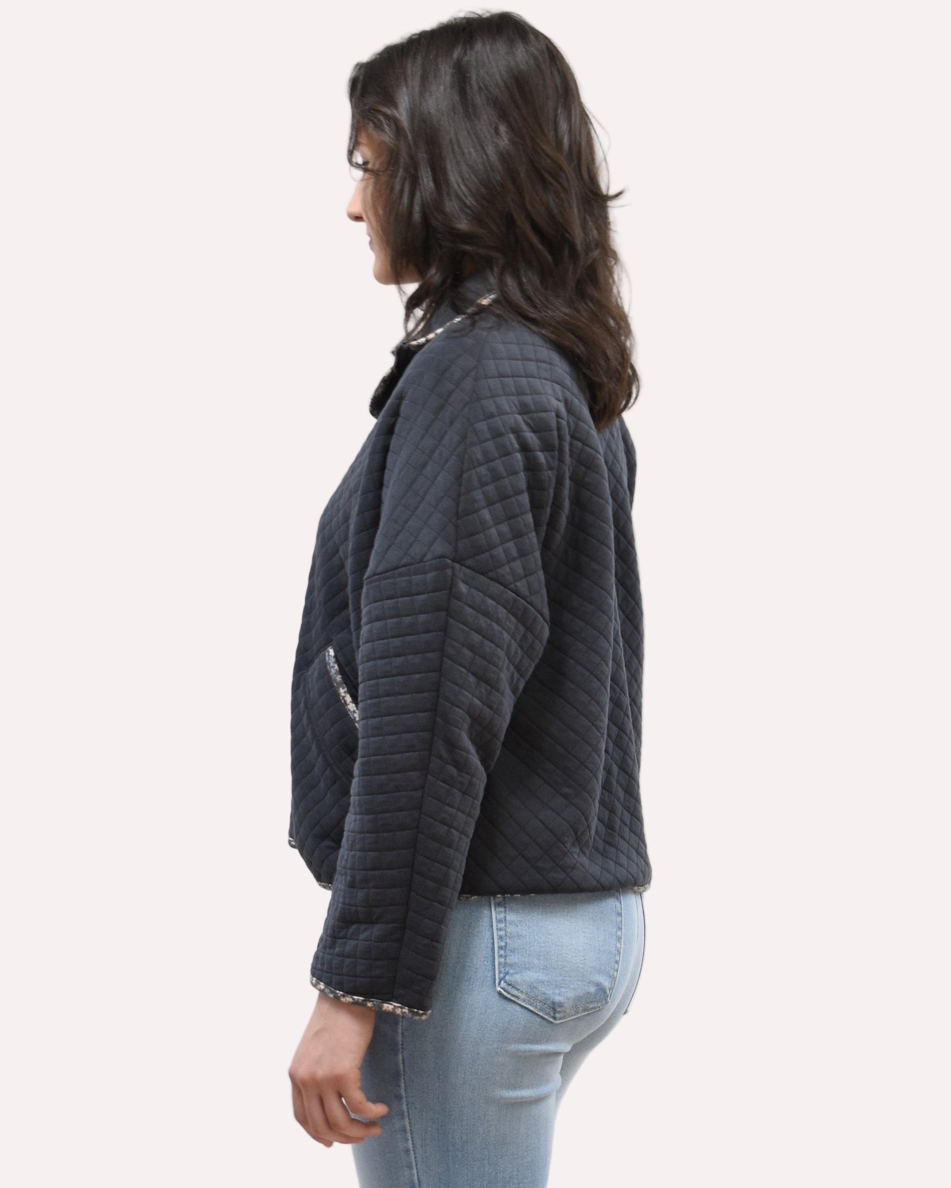 Side view of the quilted floral contrast zip-up jacket showing the mock neck, side pockets, and feminine detailing.