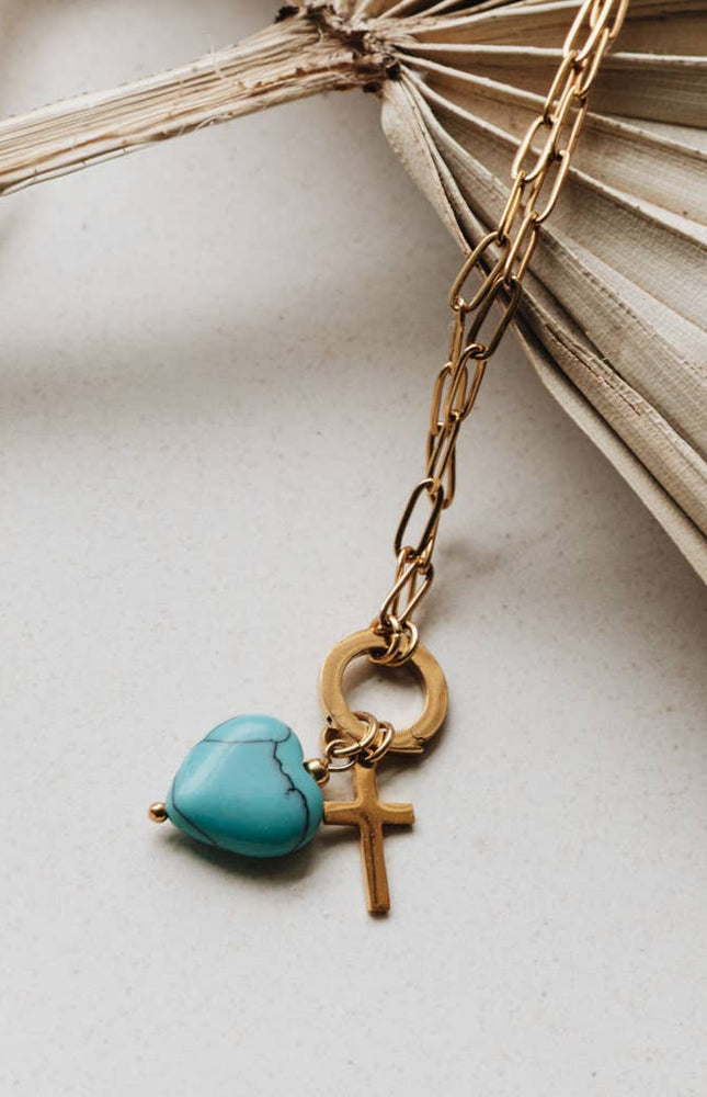 Radiant Heart Necklace — turquoise heart pendant with 14K gold-plated cross charm on waterproof chain from Justyna Grace Boutique.