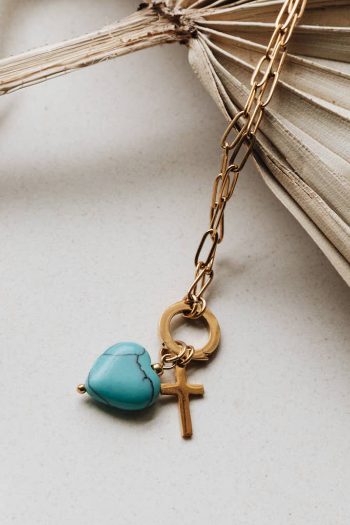 Radiant Heart Necklace — turquoise heart pendant with 14K gold-plated cross charm on waterproof chain from Justyna Grace Boutique.