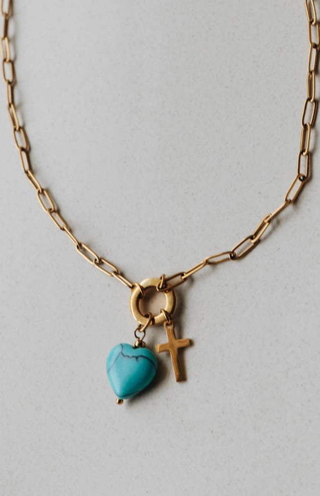 Radiant Heart Necklace — turquoise heart pendant with 14K gold-plated cross charm on waterproof chain from Justyna Grace Boutique.