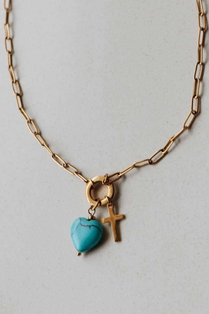Radiant Heart Necklace — turquoise heart pendant with 14K gold-plated cross charm on waterproof chain from Justyna Grace Boutique.