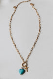Radiant Heart Necklace — turquoise heart pendant with 14K gold-plated cross charm on waterproof chain from Justyna Grace Boutique.