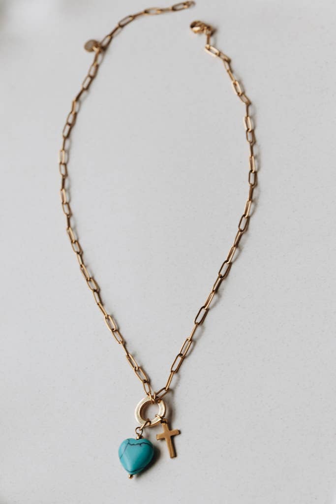 Radiant Heart Necklace — turquoise heart pendant with 14K gold-plated cross charm on waterproof chain from Justyna Grace Boutique.