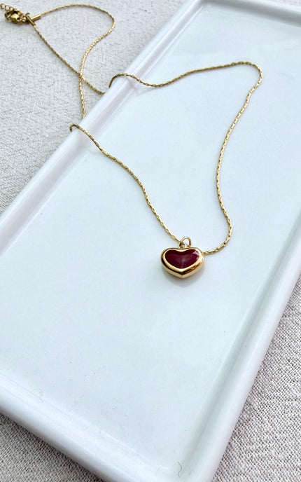 Detailed view of minimalist red heart design on delicate gold pendant