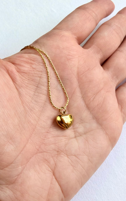 Back view of minimalist red heart design on delicate gold pendant