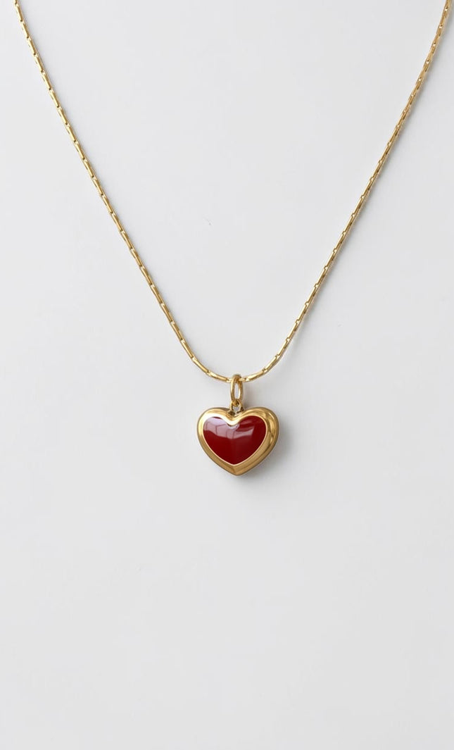 Minimalist red heart pendant necklace in 18K gold PVD displayed full length, flat lay view