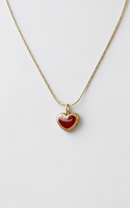 Minimalist red heart pendant necklace in 18K gold PVD displayed full length, flat lay view