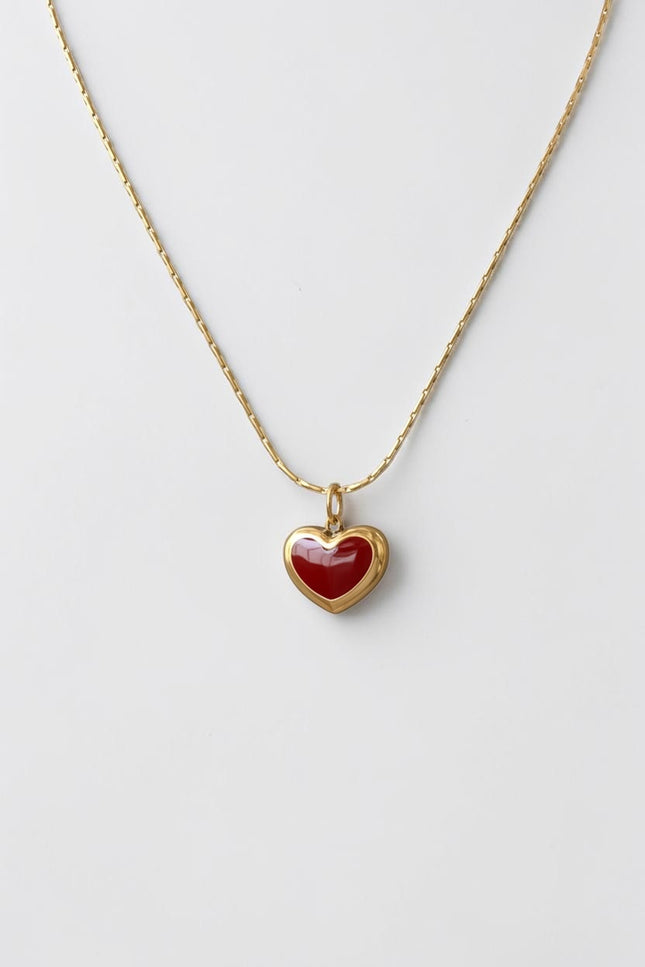 Minimalist red heart pendant necklace in 18K gold PVD displayed full length, flat lay view