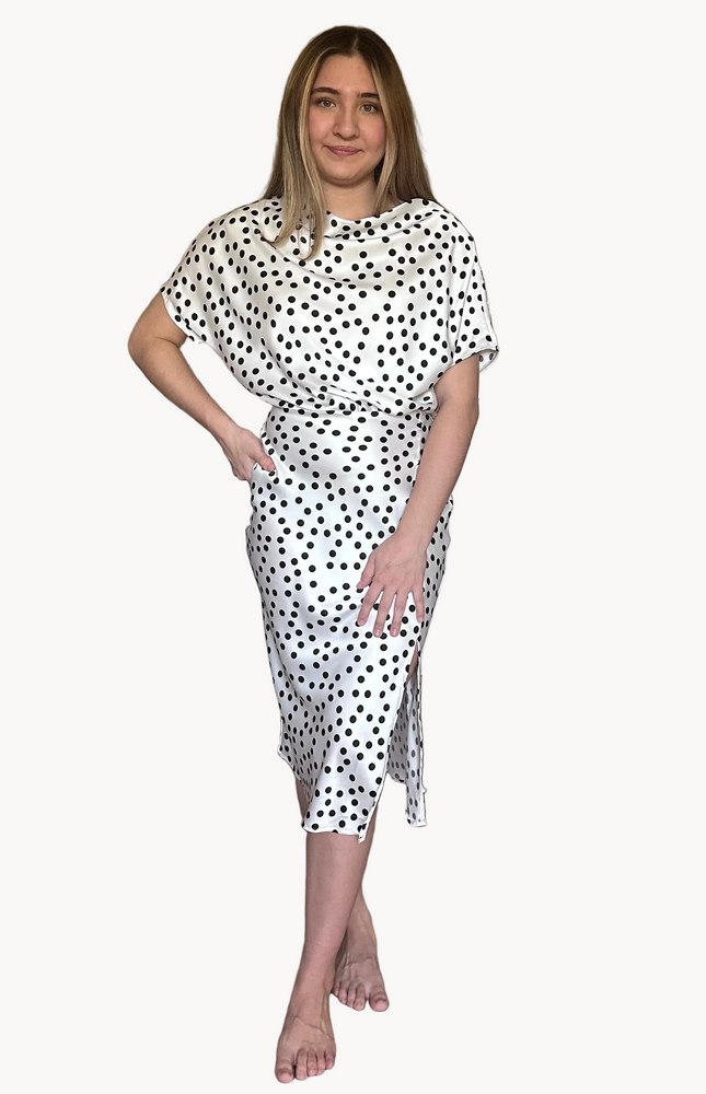 Woman wearing a white dress with black polka dots on a white background
