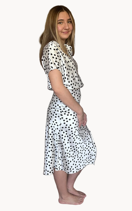Woman wearing a white dress with black polka dots on a white background