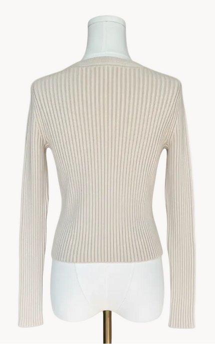 Beige ribbed sweater on a mannequin against a light pink background