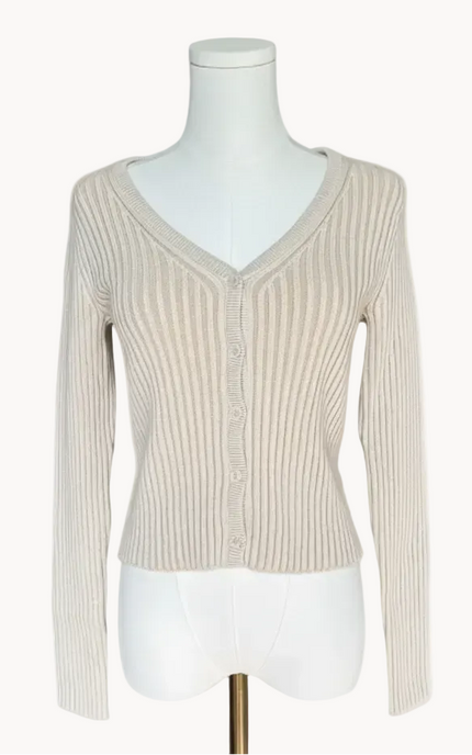 Beige ribbed sweater on a mannequin against a light pink background