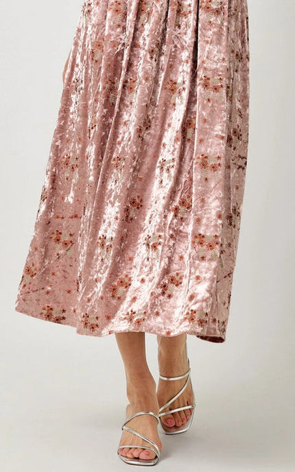 Pink floral skirt with silver strappy sandals on a plain background
