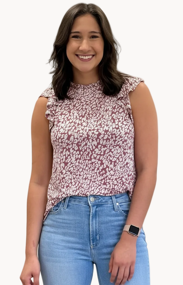 Woman wearing a floral top and blue jeans against a plain background
