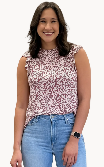 Woman wearing a floral top and blue jeans against a plain background