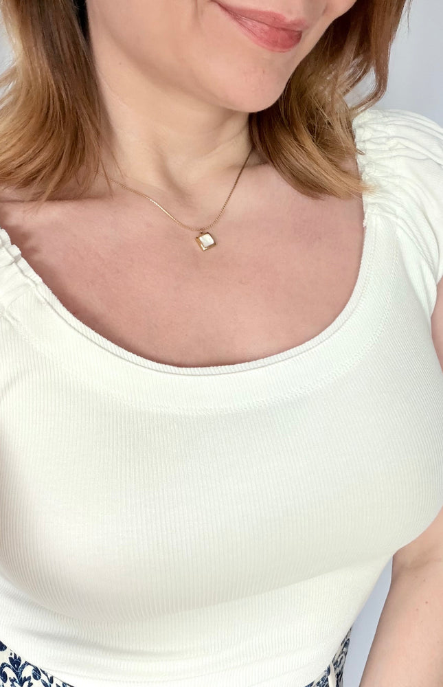 Front portrait view of a model wearing the Shell Inlay Pendant Necklace from Justyna Grace Boutique, illustrating how the clean square white shell pendant sits beautifully along the collarbone.