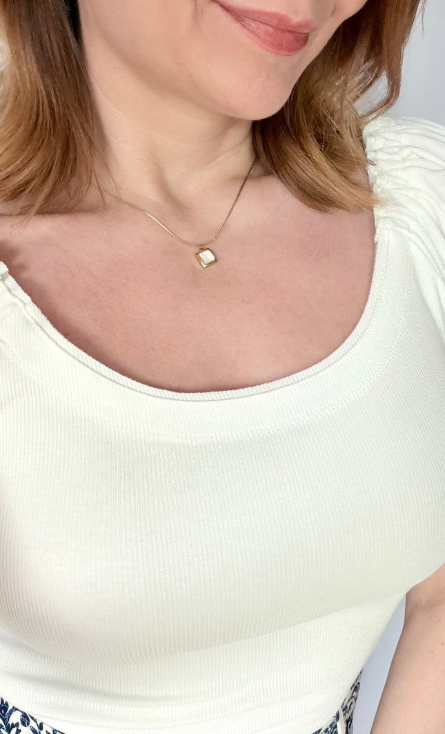 Front portrait view of a model wearing the Shell Inlay Pendant Necklace from Justyna Grace Boutique, illustrating how the clean square white shell pendant sits beautifully along the collarbone.