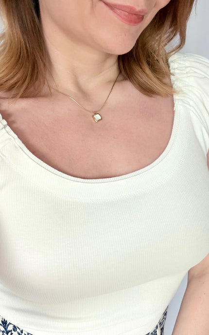 Front portrait view of a model wearing the Shell Inlay Pendant Necklace from Justyna Grace Boutique, illustrating how the clean square white shell pendant sits beautifully along the collarbone.