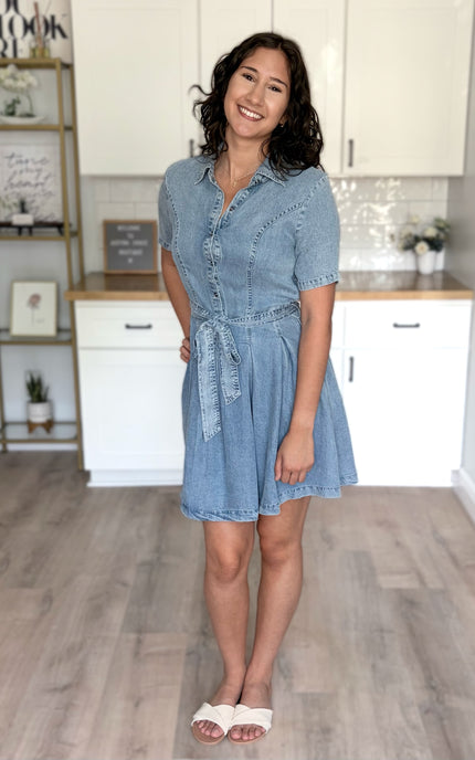 Feminine light-wash shirt dress with short sleeves, button-front closure, and tied waist detail