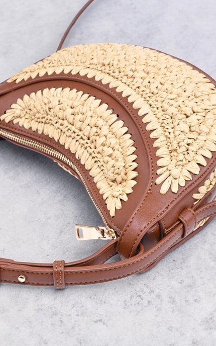 Minimalist crescent crossbody bag featuring woven texture and zip-top closure, flat lay