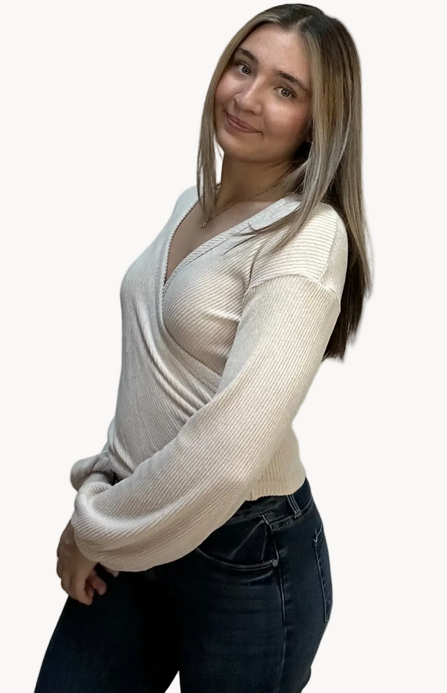 Woman wearing a white long-sleeve top over a sheer top on a plain background