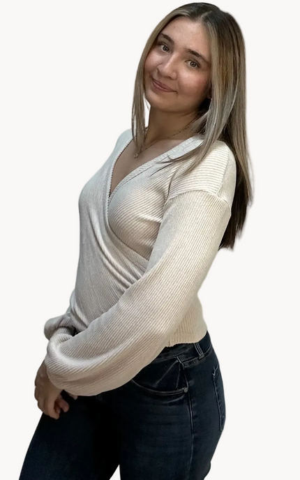 Woman wearing a white long-sleeve top over a sheer top on a plain background