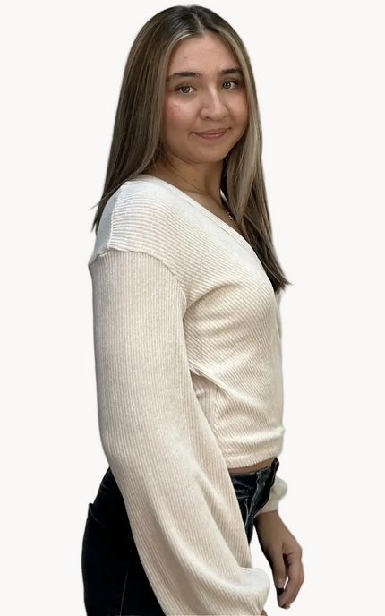 Woman wearing a cream sweater against a plain background