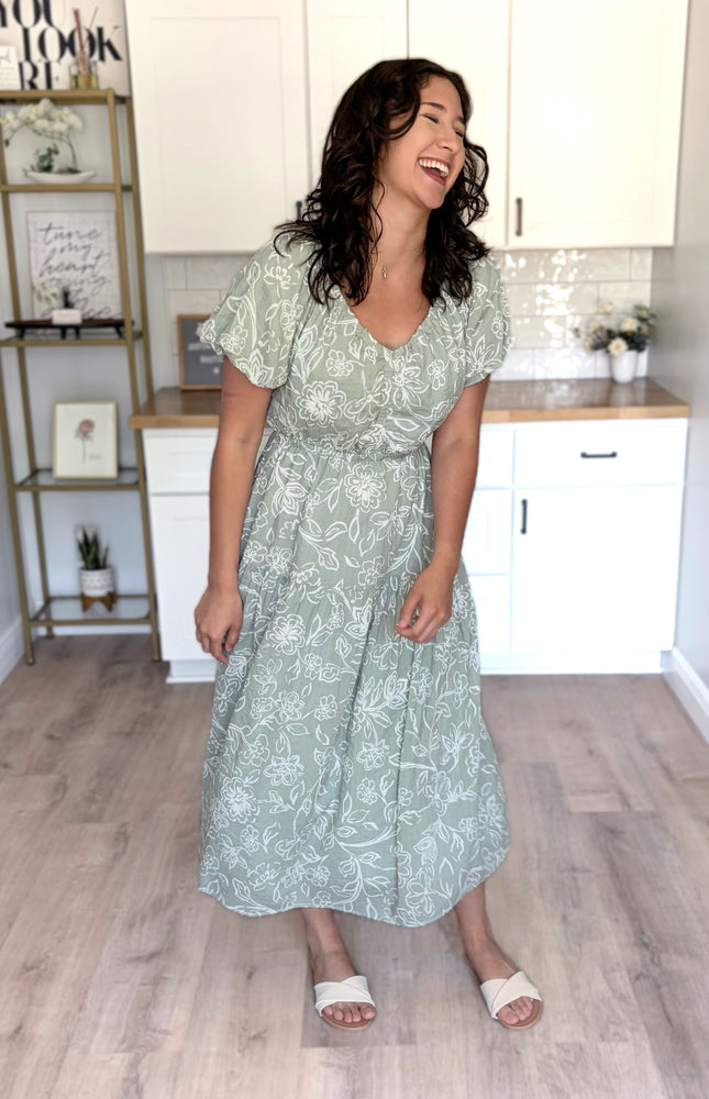 Feminine V-neckline midi dress with puff sleeves, elastic waist, and tiered skirt with pockets