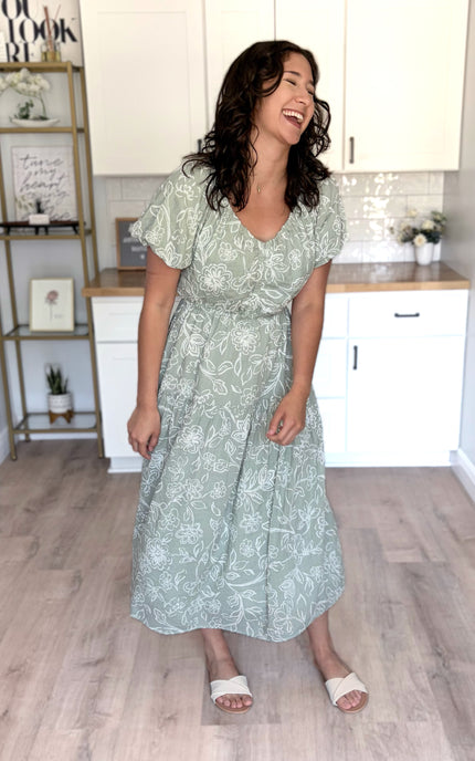 Feminine V-neckline midi dress with puff sleeves, elastic waist, and tiered skirt with pockets