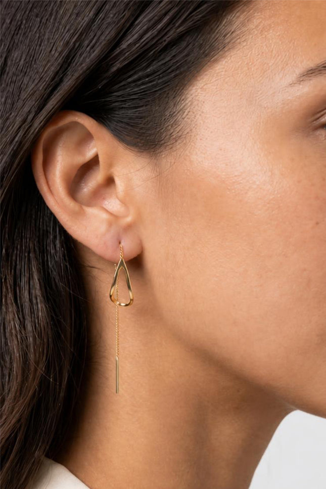 Extreme close-up side profile shot of the model's ear, highlighting the seamless, fluid drape of the 6cm thread-through chain as it loops elegantly through the piercing.