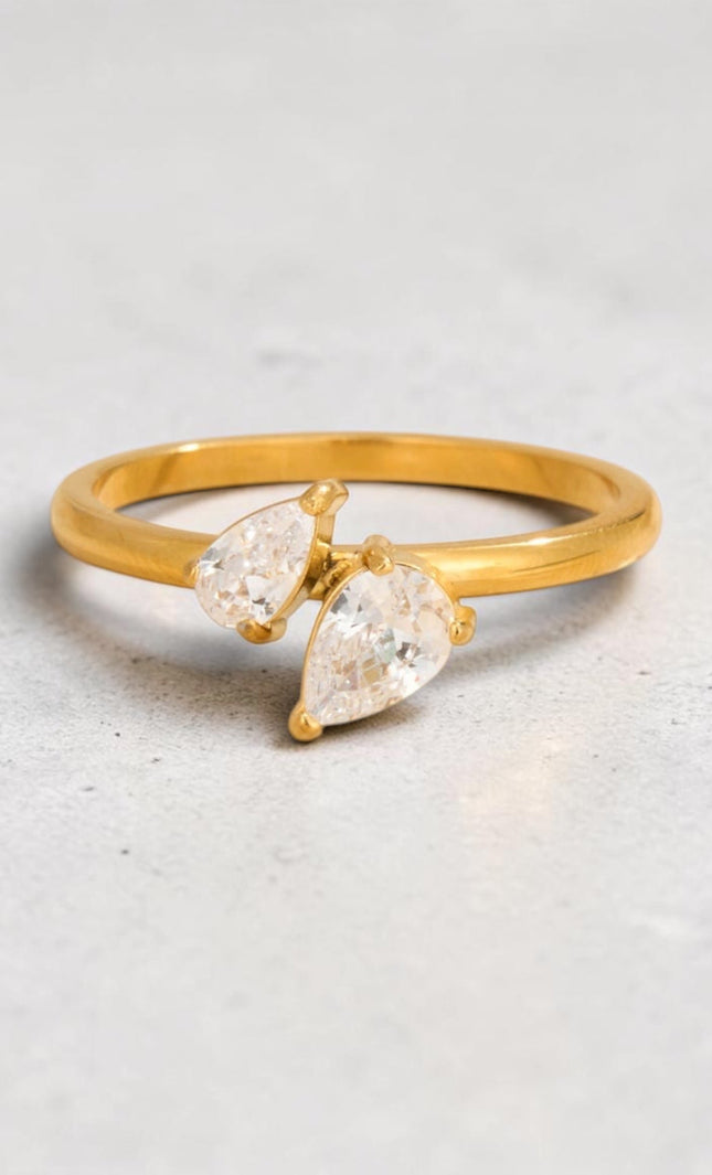 Gold PVD ring featuring two teardrop-cut crystals, flat lay view