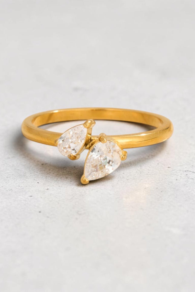 Gold PVD ring featuring two teardrop-cut crystals, flat lay view