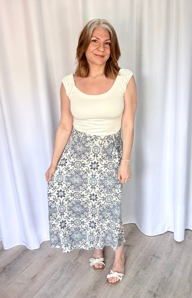 Full-length view of the Valencia Tile Midi Skirt from Justyna Grace Boutique, featuring a tile-inspired geometric print and a matching circle buckle belt.