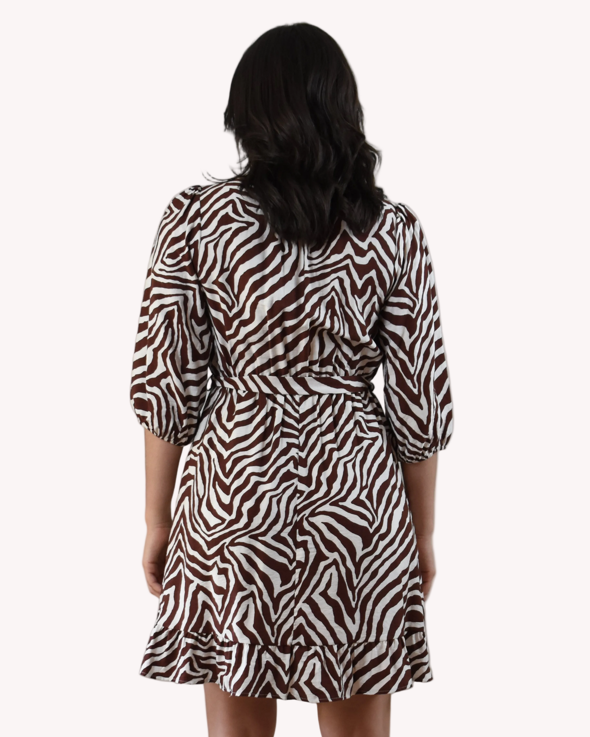 The Wild Grace Zebra Tie Dress in ivory and brown — round neckline, 3/4 sleeves, and adjustable waist tie from Justyna Grace Boutique.